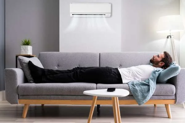 Happy man relaxing on a sofa enjoying fresh, cool indoor air from a clean ventilation system