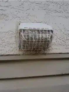 Clogged dryer vent cap covered in lint buildup requiring professional cleaning